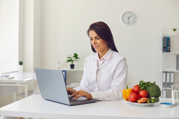 Dietitian using laptop making diet plan or giving consultation for clients online